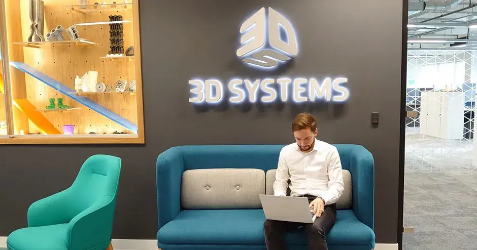 A man sitting in a 3D Systems lounge and working on his laptop